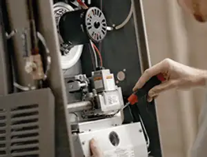 Furnace repair technician inspecting internal components and wiring in Providence, RI