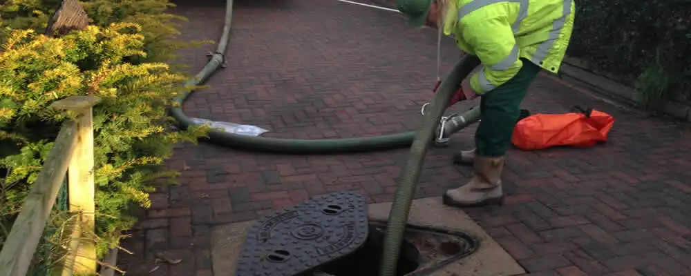 Septic tank cleaning technician servicing a septic tank with a vacuum hose in Providence, RI