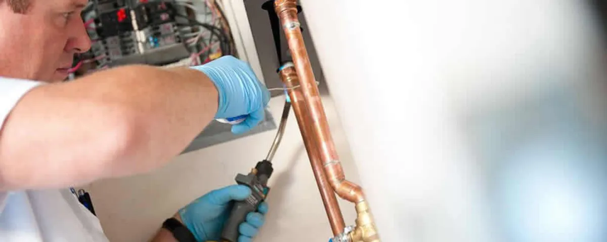 Water heater repair technician testing copper pipe connections and controls in Providence, RI